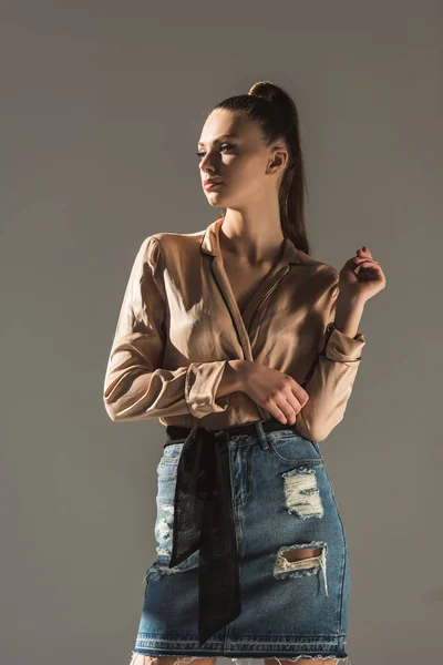 Attractive girl posing in blouse and denim skirt, isolated on grey — Stock Photo