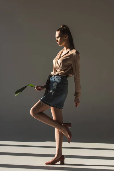 Mujer joven de moda en falda de mezclilla y blusa con hoja verde - foto de stock