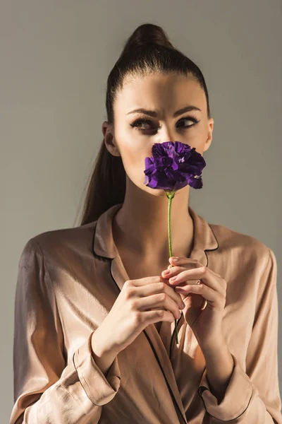 Schönes stylisches Mädchen mit lila Eustoma-Blume, isoliert auf grau — Stockfoto