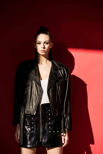 Красивая девушка позирует в черной кожаной куртке для модной съемки на красный — стоковое фото