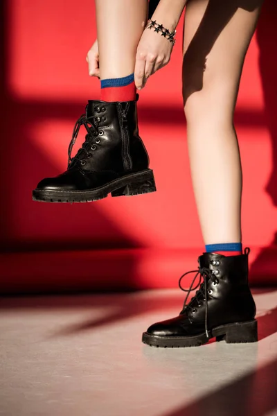 Sección baja de la niña posando en zapatos negros en rojo - foto de stock