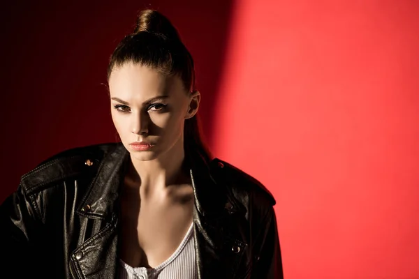 Portrait de jeune femme séduisante posant en veste en cuir noir pour le tournage de mode sur rouge — Photo de stock