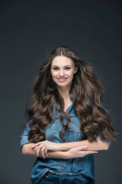 Hermosa chica alegre con el pelo largo posando en camisa de mezclilla, aislado en gris - foto de stock