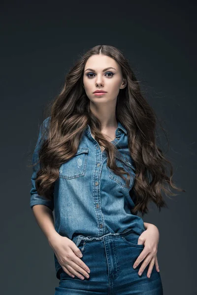 Jolie fille aux cheveux longs posant dans des vêtements en denim, isolé sur gris — Photo de stock