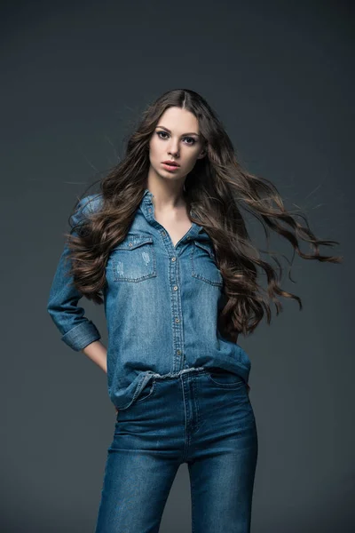 Chica atractiva con el pelo largo posando en jeans, aislado en gris - foto de stock