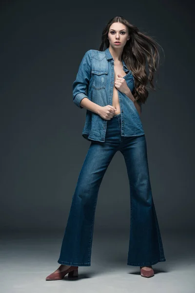 Привлекательная сексуальная девушка позирует в джинсовой одежде, на серой — стоковое фото