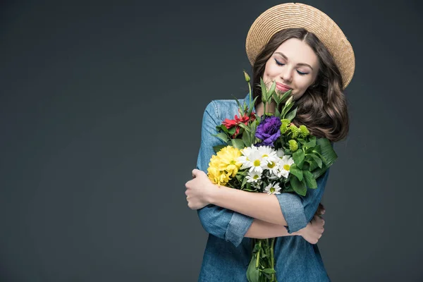 Hermosa mujer feliz con los ojos cerrados sosteniendo flores para 8 marzo, aislado en gris - foto de stock