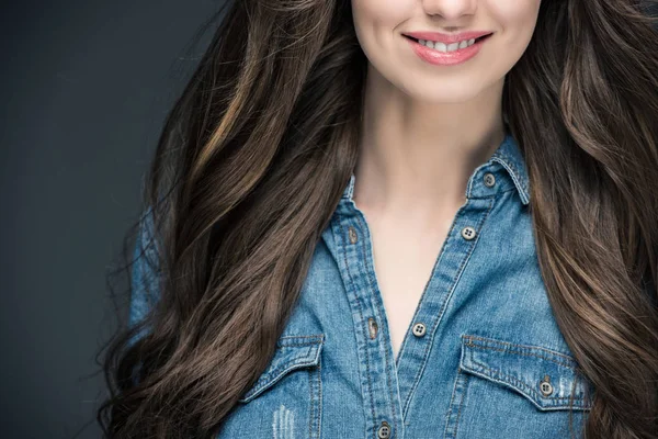 Abgeschnittene Ansicht eines lächelnden brünetten Mädchens mit langen Haaren, isoliert auf grau — Stockfoto