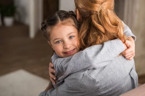 Madre abrazando adorable hijita en casa - foto de stock