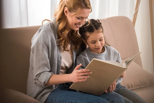 Mère heureuse et petite fille lecture livre ensemble à la maison — Photo de stock