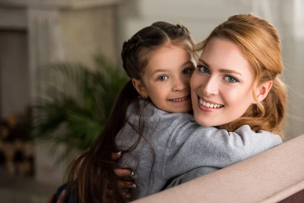Schöne glückliche Mutter und Tochter umarmen und lächeln in die Kamera zu Hause — Stockfoto