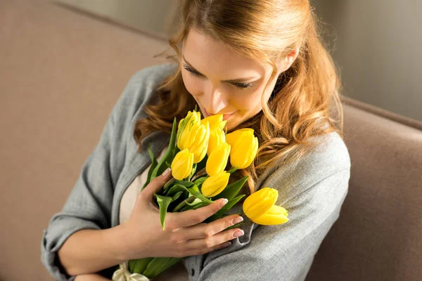 Schöne lächelnde junge Frau mit gelben Tulpen zu Hause — Stockfoto