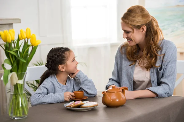 Happy mother and daughter drinking tea and smiling each other — Stock Photo