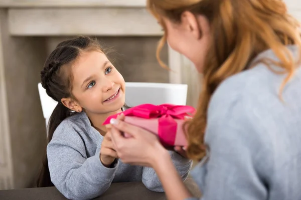 Selective focus of adorable smiling child presenting gift box to mother — Stock Photo