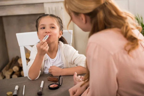 Selective focus of mother and little daughter applying makeup together at home — Stock Photo