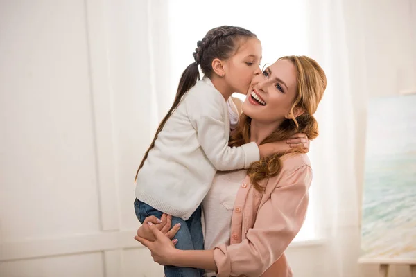 Lindo pequeño niño besando feliz madre en casa - foto de stock