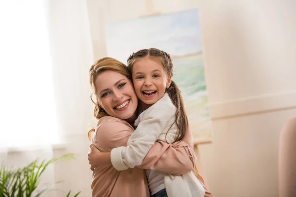 Felice madre e figlia abbracciare e sorridere alla fotocamera a casa — Foto stock