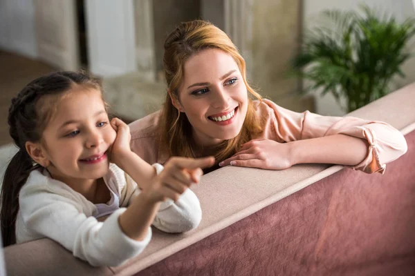 Happy mother and daughter pointing with finger and looking away — Stock Photo
