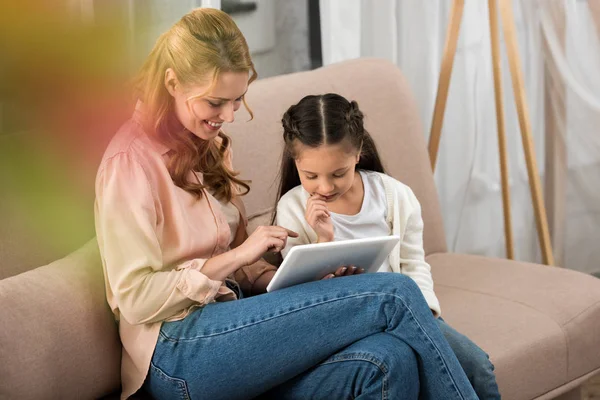 Mère heureuse et fille en utilisant la tablette numérique ensemble à la maison — Photo de stock