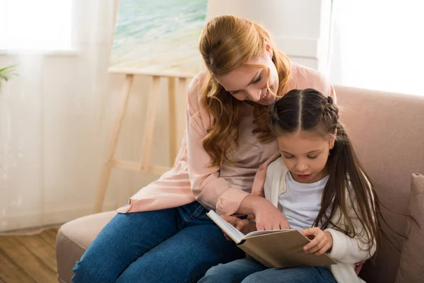 Feliz madre e hija leyendo el libro juntos - foto de stock