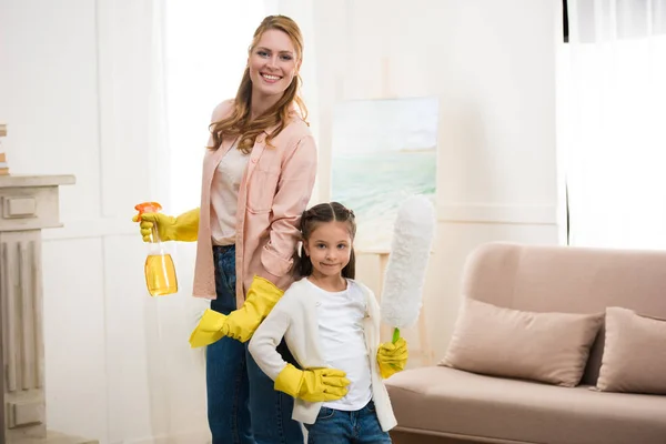 Happy mother and daughter cleaning room and smiling at camera — Stock Photo