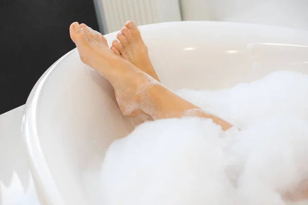 Tiro recortado de piernas femeninas en baño con espuma - foto de stock