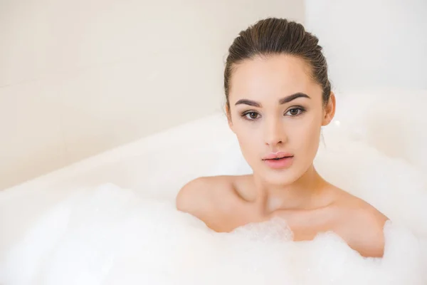 Ritratto di attraente giovane donna che fa il bagno con schiuma a casa — Foto stock