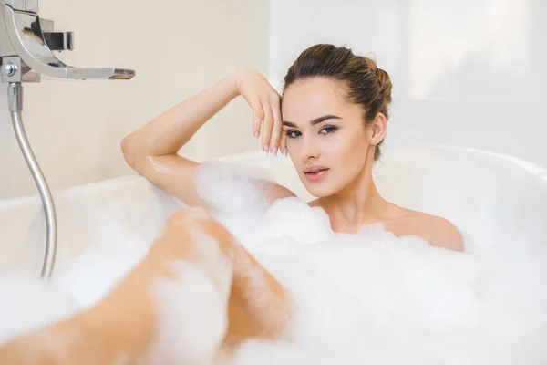Atractiva mujer joven tomando baño con espuma en casa - foto de stock