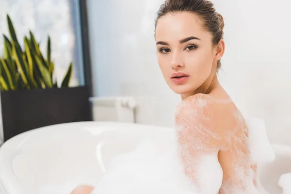 Vista lateral de la hermosa mujer joven tomando baño en casa - foto de stock