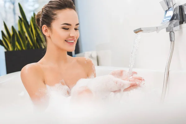 Souriant jeune femme prenant un bain à la maison — Photo de stock