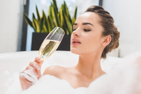 Portrait of beautiful woman with glass of champagne taking bath — Stock Photo
