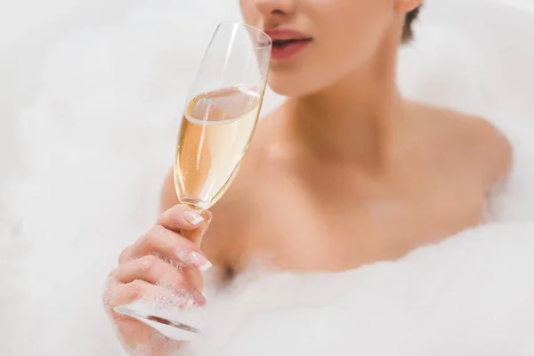 Частковий вид на красиву жінку зі склянкою шампанського приймаючи ванну — стокове фото
