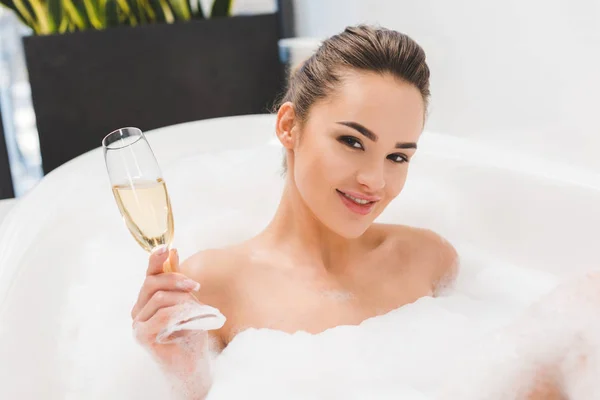 Hermosa mujer con copa de champán tomando baño - foto de stock