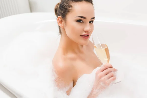 Hermosa mujer con copa de champán tomando baño - foto de stock