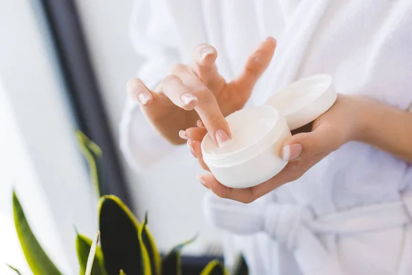 Partial view of woman holding face cream in hands — Stock Photo