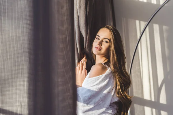 Mulher muito pensativo em roupão de banho de pé na janela em casa — Fotografia de Stock