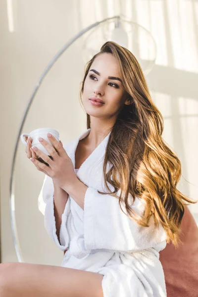 Retrato de bela jovem mulher em roupão de banho com xícara de café em casa — Fotografia de Stock