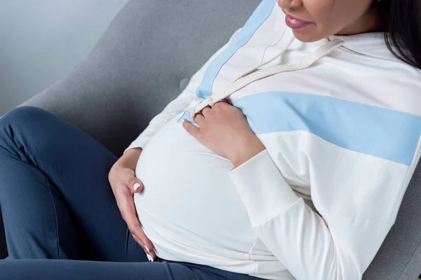 Cropped view of african american pregnant woman sitting in armchair — Stock Photo