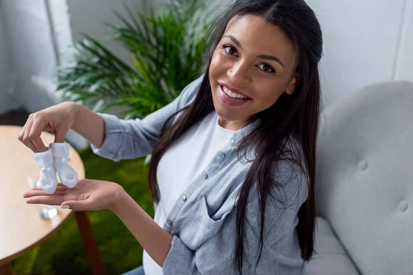 Felice donna africana incinta americana che tiene piccoli calzini — Foto stock