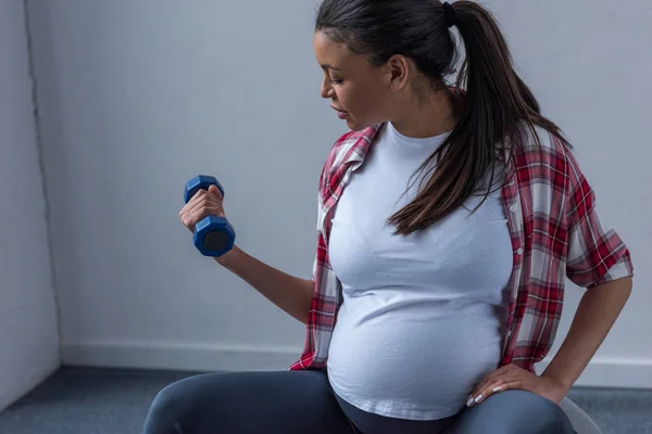 Африканская беременная женщина тренируется с гантелями — стоковое фото