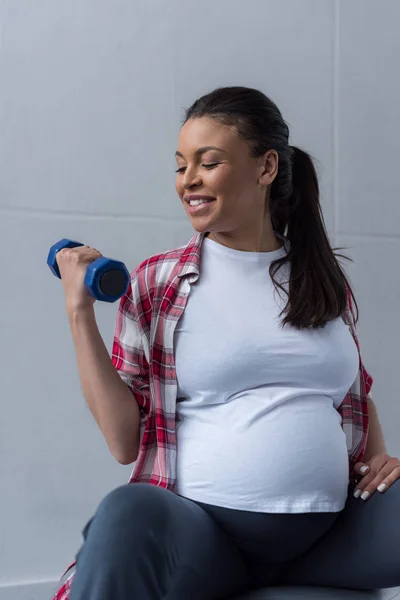Feliz africano americano embarazada mujer ejercicio con dumbbell - foto de stock