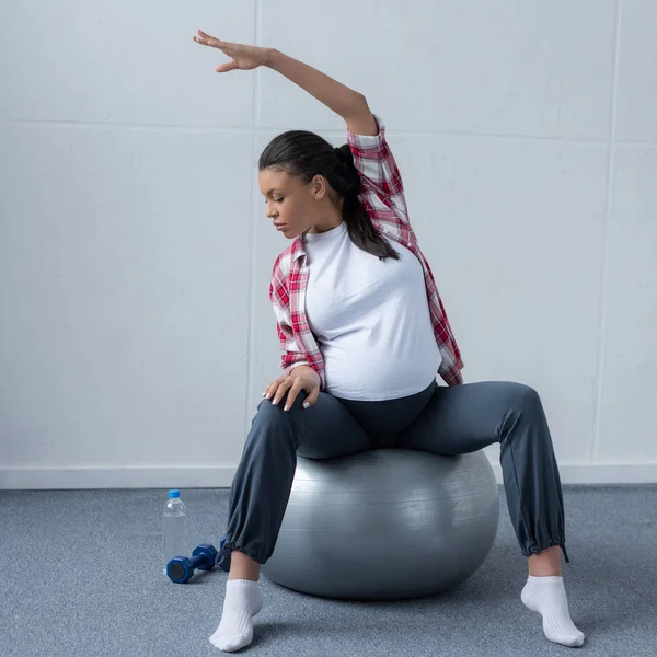 African american pregnant woman stretching on fit ball — Stock Photo