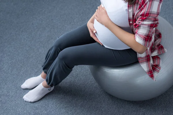 Ausgeschnittene Ansicht einer schwangeren Frau, die auf einem Ball sitzt — Stockfoto