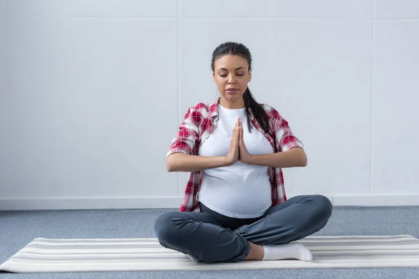 Donna africana americana incinta che pratica yoga su tappetino — Foto stock