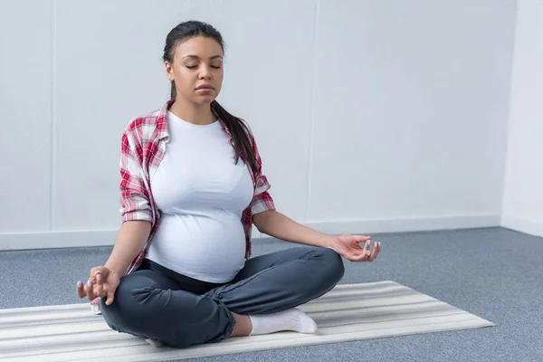 Afrikanisch-amerikanische schwangere Frau praktiziert Yoga auf Matte — Stockfoto