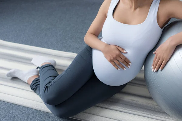 Visão cortada da mulher grávida sentada com bola em forma — Fotografia de Stock