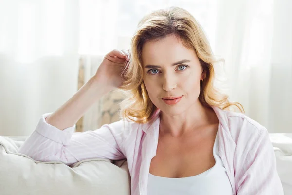 Blonde woman in pajamas sitting on sofa at home — Stock Photo