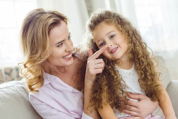 Feliz madre tocando la nariz de su hija rizada - foto de stock