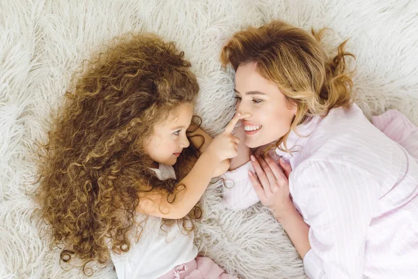Top view of adorable curly daughter touching nose of her mom — Stock Photo