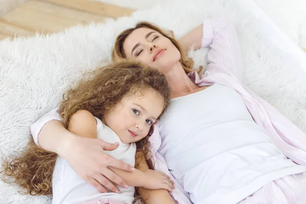 Bella madre e adorabile figlia riccia rilassante sulla coperta di pelle di pecora — Foto stock